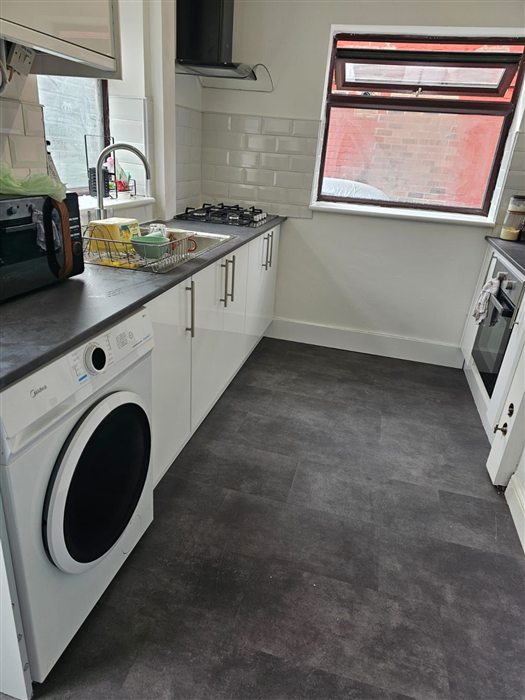 Same galley kitchen after: white gloss units, dark worktop and metro tiles