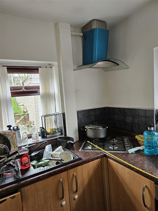 Galley kitchen before: dated wood-effect units and a cluttered worktop