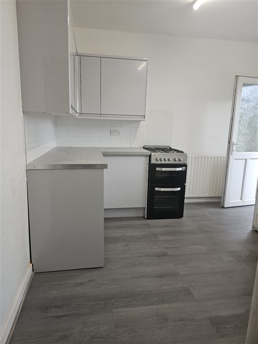 Same kitchen after: light grey gloss units and grey plank flooring