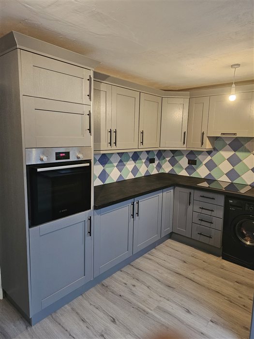 Blue-grey shaker kitchen with patterned splashback tiles